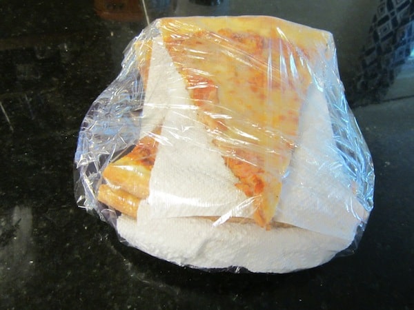 pizza wrapped in saran wrap and paper towels 
