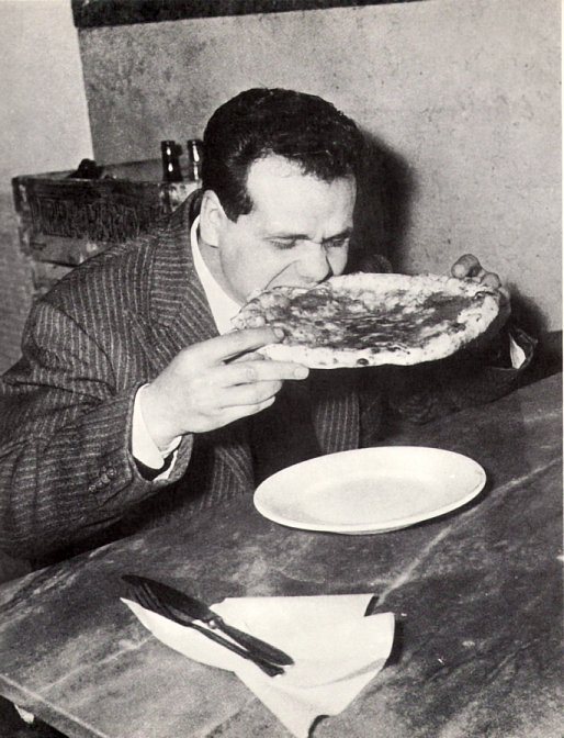 Vintage man eating pizza while using both hands.