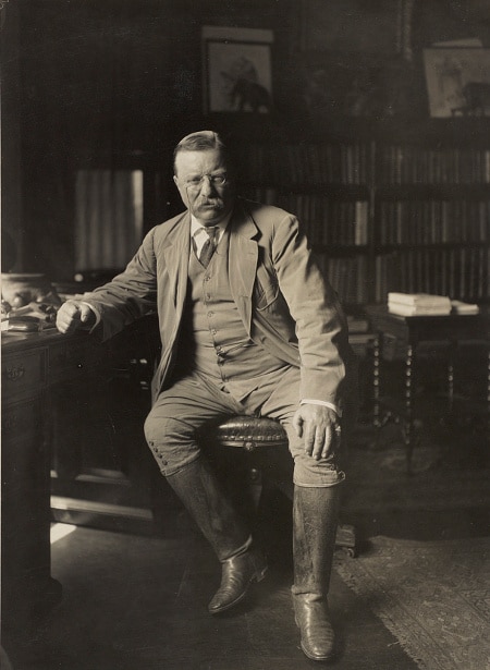 Teddy Theodore sitting on chair and wearing riding boots.