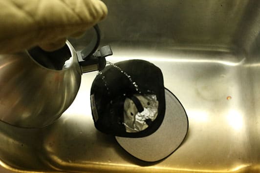 pouring hot water onto baseball cap hat 