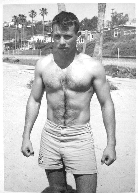 Vintage man in swim trunks at beach strong physique. 