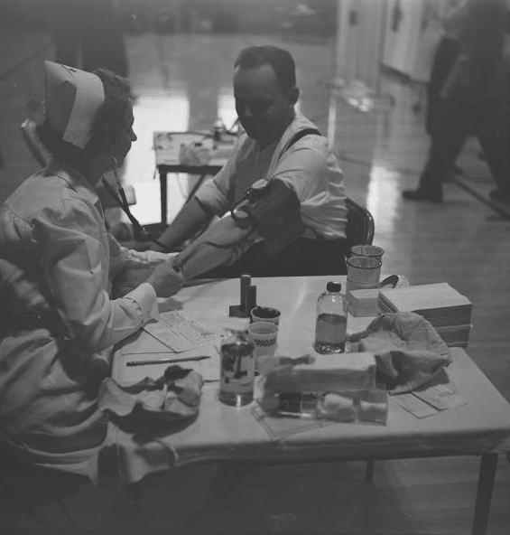 Vintage man sitting at nurse table and checking blood pressure. 