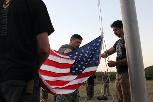 men at flagpole raising american flag