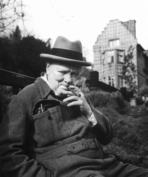 Winston Churchill sitting on Bench smoking Cigar.