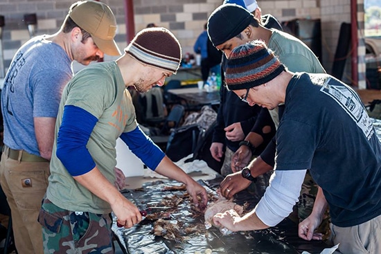 plucking a chicken men gathered around a table