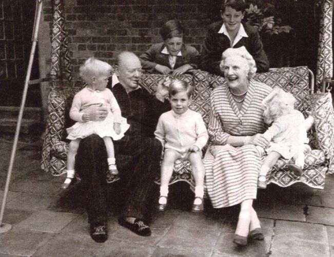 Winston Churchill with wife and grandchildren on outdoor swing.