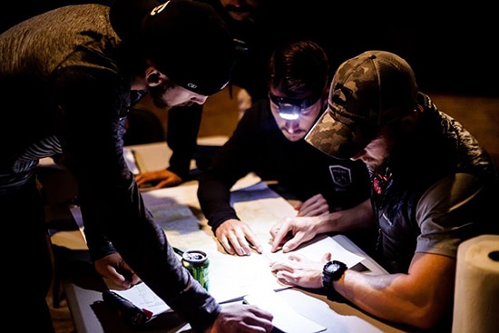 men gathered around topographic topo map land navigation