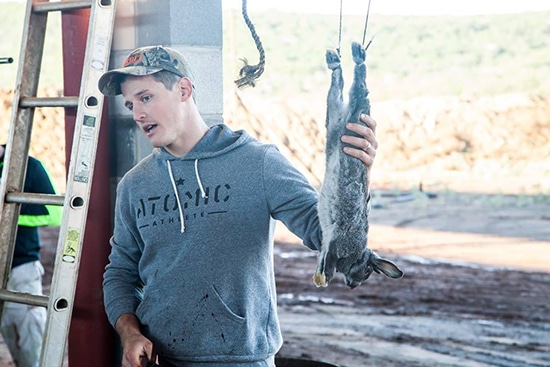 man field dress butcher rabbit strung up