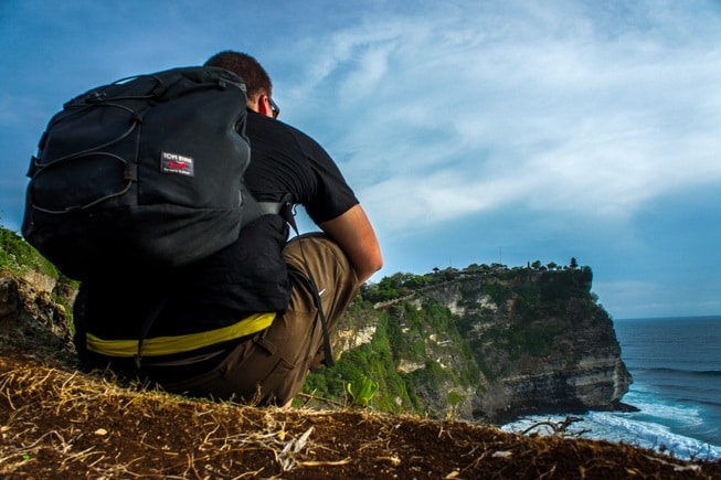 Man sitting on edge of Cliff with Backpack. 