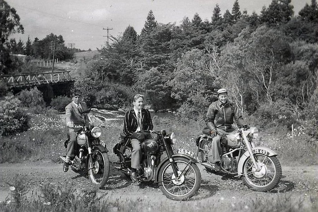 Vintage men on motorcycles on trail near river. 