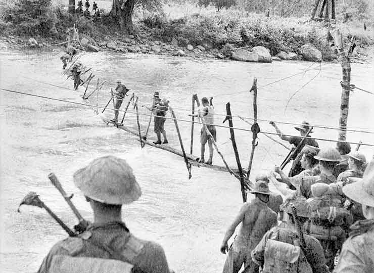 Vintage men walking across bridge over river. 