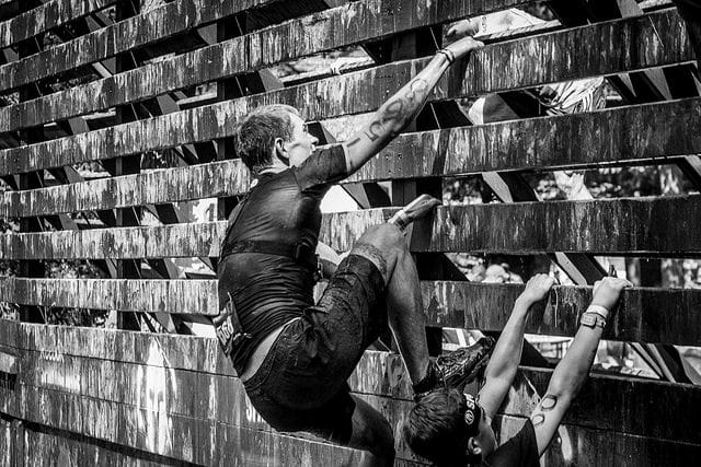 Man climbing wall during obstacle race.