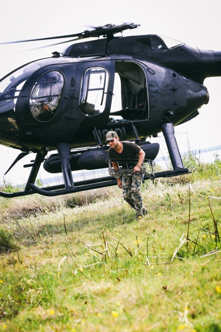 Man getting out of helicopter for hunting trip expedition.