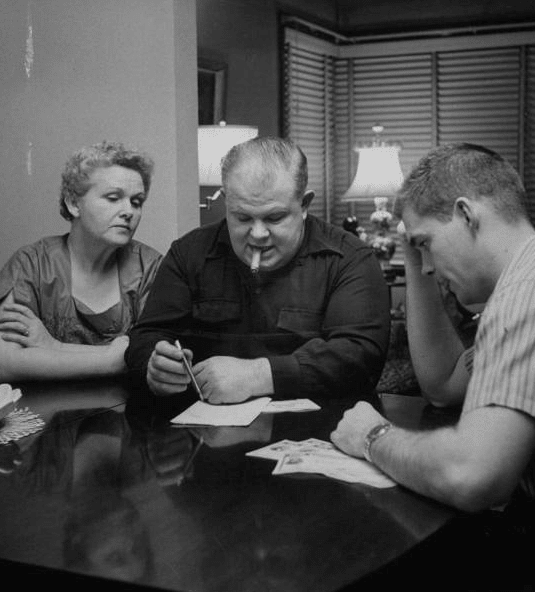 Vintage family at dinner table discussing allowance.