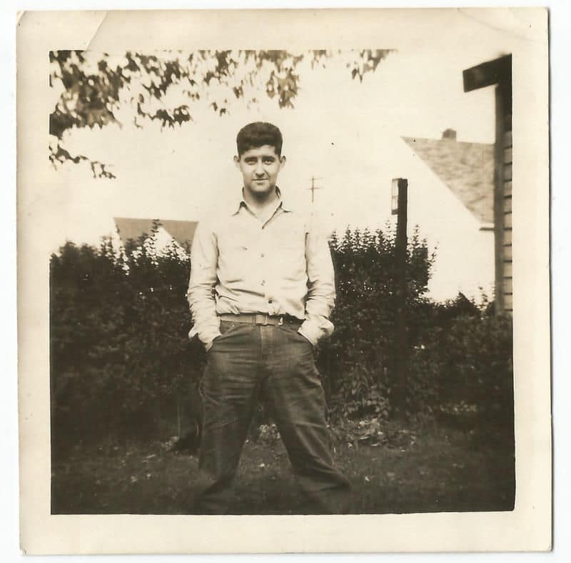 Vintage man standing in yard with hands in pockets.