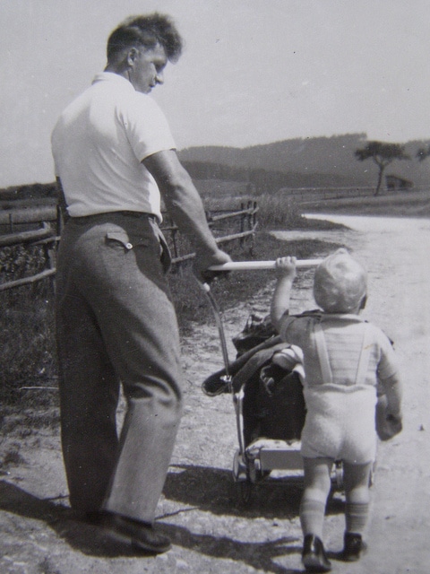 Vintage 1950s father walking with baby child.