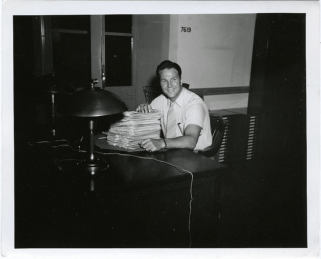 Vintage man on desk with stack of paperwork.