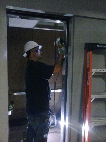 Man doing work in elevator with cutter and ladder.