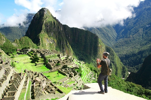 Traveler taking picture with cell phone in Machu Picchu, Peru