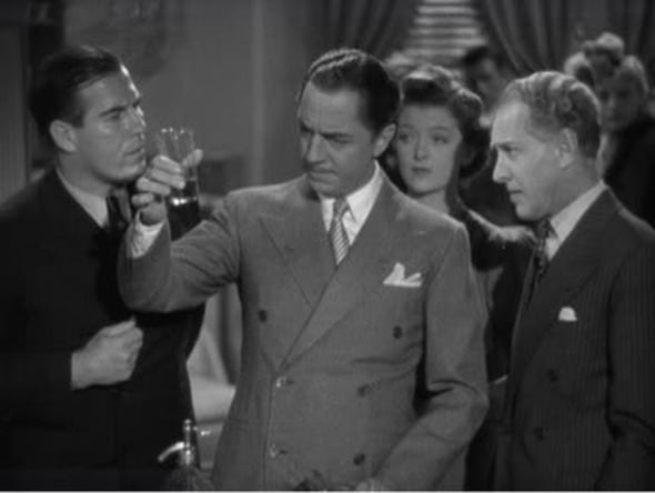 Vintage man in suit looking thoughtfully at glass of whiskey.