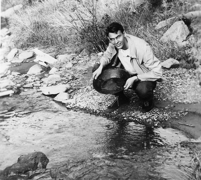 Vintage man gold panning prospecting on small stream.