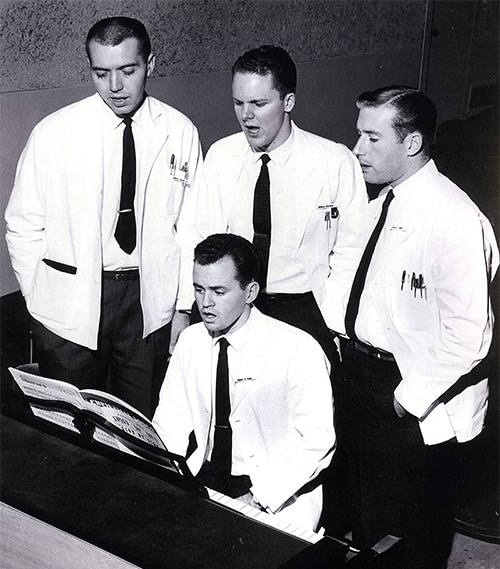 Vintage men doctors white coats singing in group.