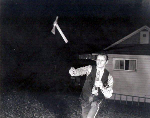 Vintage man throwing tomahawk ax mid-air.