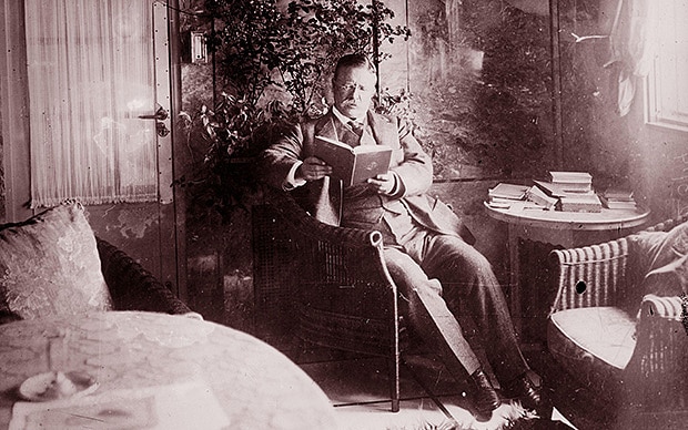 Theodore roosevelt reading a book in sitting room. 