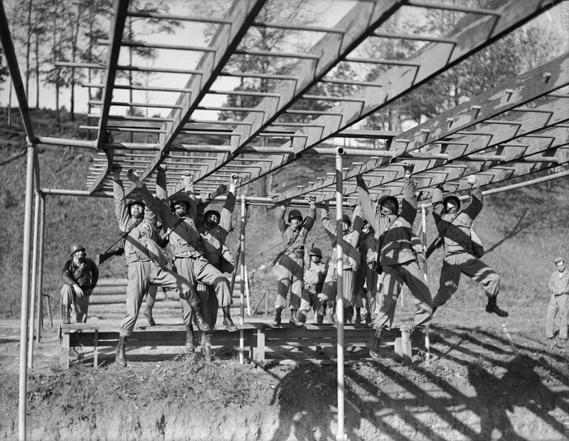 Vintage boot camp basic training soldiers doing monkey bars.