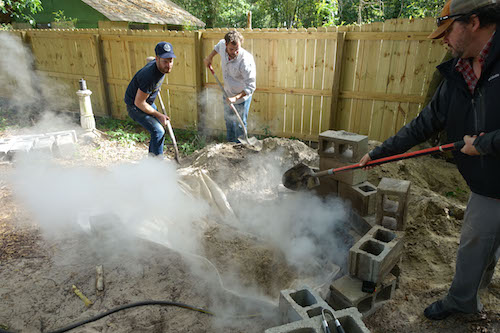 Men adding soil for looking spots on pig meat.