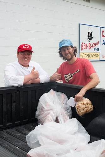 Two men are packing 100 pound of pig meat at butcher shop.