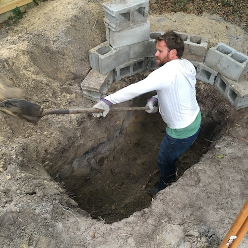 A man digging a square shape grave with blocks.