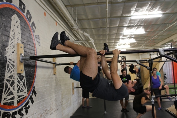 man hanging upside down from bar like sloth movnat workshop