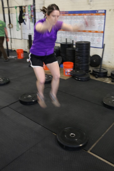 woman jumping from weight plate to weight plate movnat workshop