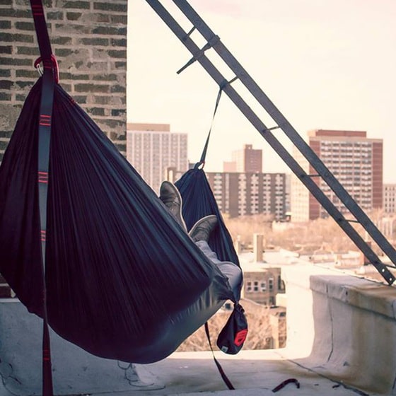 man sleeping in hammock on city rooftop