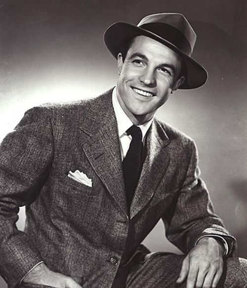 Vintage man in suit and fedora smiling. 