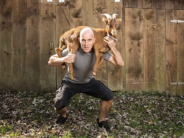 Chris mcdougall writer lifting holding goat on shoulder. 