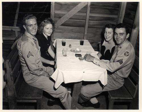 Vintage soldiers sitting with his wives at table.