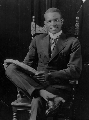 A young man in a suit, exuding an air of sincerity, sitting in a chair.