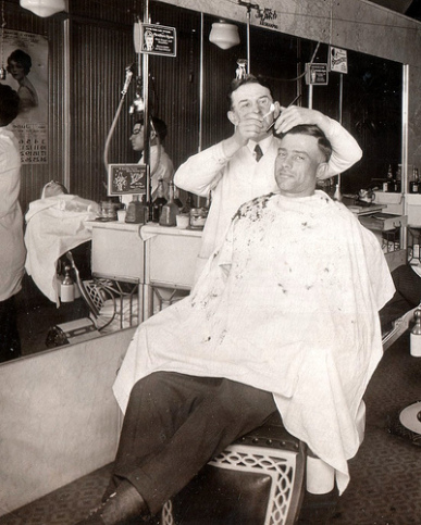 Vintage man getting haircut at barbershop.