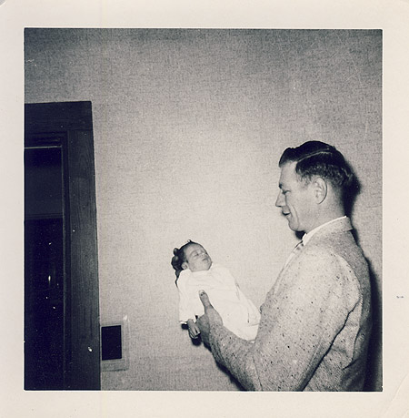 Vintage father holding newborn in room.