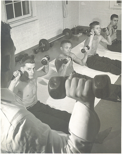 Vintage young men lifting weights in gym. 