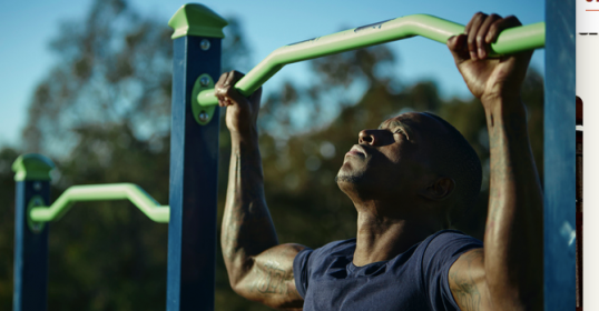 A man is performing pull-ups on a bar as part of his strength training routine.