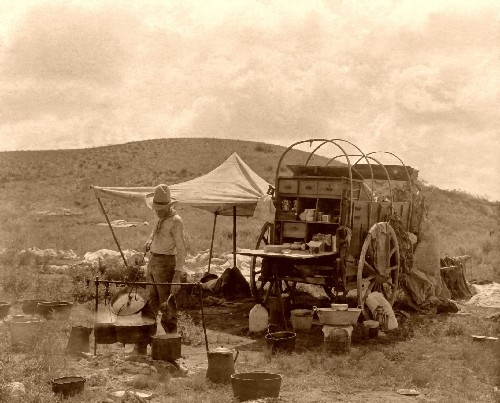 Cowboy cooking meal for camp on wagon.