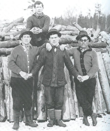 Vintage group of male friends standing and one sitting on the log.