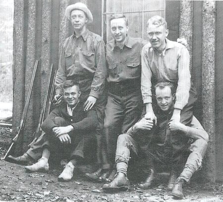 Vintage male friends together along with rifles. 