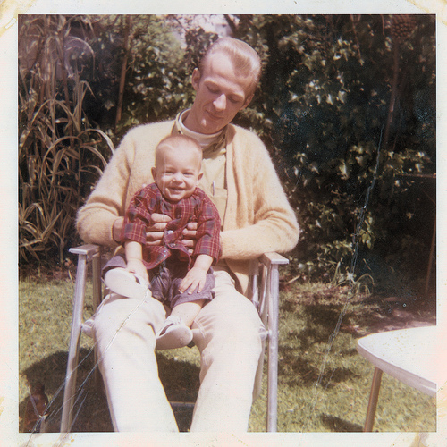 An awesome dad holding a baby in a chair, utilizing his Fatherhood Tips.