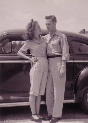 Vintage young couple in front of car.