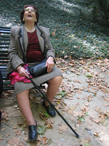 Grandma on a bench with a cane laughing.