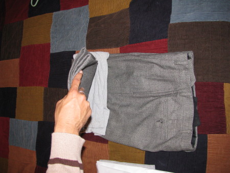 Man folding slacks pack dress pants.